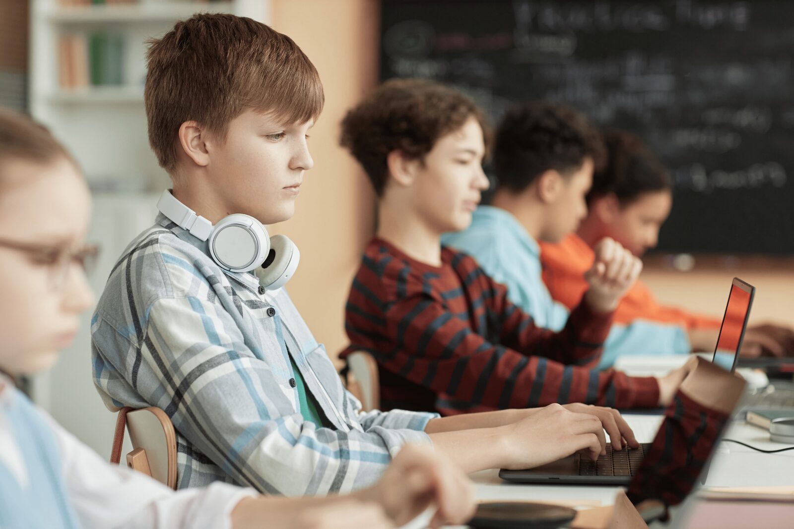 Paaugliai kompiuterių klasėje mokosi programavimo su nešiojamaisiais kompiuteriais
